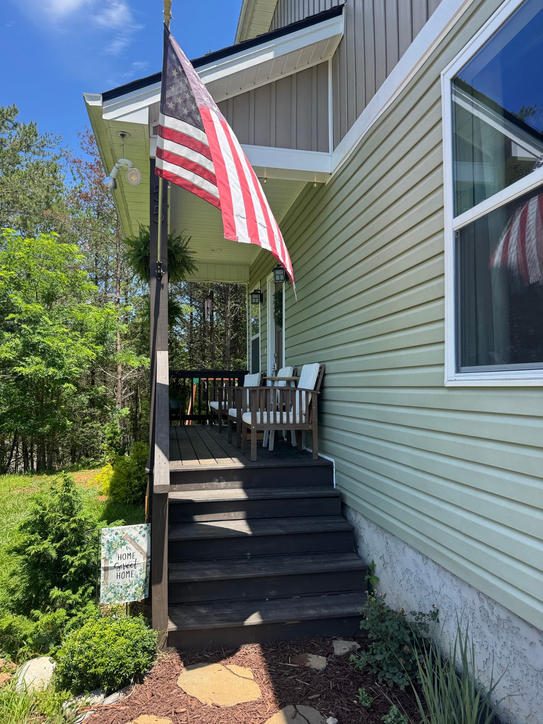Side view of porch stairs with outdoor seating and hanging ferns