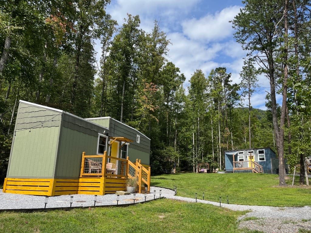 Treetop Oaks tiny cabin on a grassy clearing with wooded hills beyond